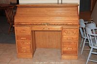 Front view of oak roll-top desk closed, showing two pedestals each with four drawers