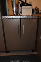 Front view of Coleman heavy duty storage cabinet with closed doors, diamond plate top, and silver handles.