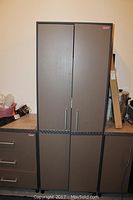 Front view of grey Coleman heavy duty storage cabinet with straight vertical doors and silver handles.