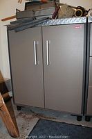 Exterior front view of gray Coleman storage cabinet with diamond plate top and silver handles.