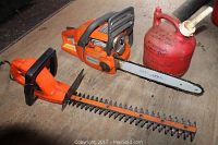 Side view of Husqvarna chainsaw, Craftsman hedge trimmer, and red gas can on floor.
