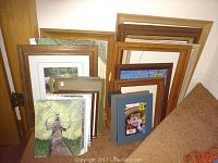 Stack of assorted wooden picture frames in various sizes leaning against a wall