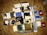 Wide view of assorted jewelry boxes open displaying necklaces, earring sets, a wristwatch, and bangles arranged on a tray.