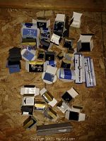 Multiple jewelry pieces including earrings, bracelets, rings, watches in original boxes laid on plywood surface