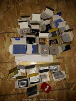 Collection of assorted jewelry pieces displayed in open boxes on a wooden surface.
