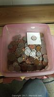 Plastic container filled with assorted mostly US and Canadian coins including one coin in a cardboard 2x2 holder.