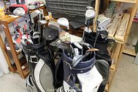 Three golf club sets in bags with assorted clubs visible