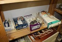 Overview photo showing all items in the lot on wooden shelves including the walker wheels box, heating pad box, diabetes monitor box, and blood glucose sensor box.
