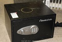 Black Sentry Safe metal home safe with electronic keypad lock, showing top and front with visible surface wear and discoloration on top.