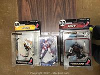 Photo of three McFarlane NHL hockey figurines in packaging showing players Jaromir Jagr, Patrick Roy, and another in blue/white/red uniform.