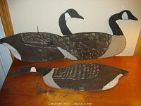 Three folk art Canada Goose silhouettes displayed on a wood surface, showing size and painting details