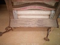 Side angle view focusing on the wooden seat-like base and cranked metal rods.