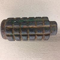 Side view of the rusted inert WW1 grenade showing its square segmented body pattern