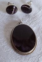 Overall view of two round earrings positioned above an oval brooch showing full set.