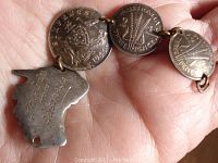 View of front side with linked three coins (6 pence and two 3 pence) and Australia-shaped charm with engraving.
