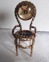 Front view of the miniature chair showing the Eastern Star emblem on the backrest and tartan fabric seat.