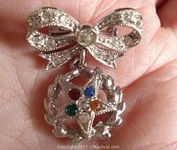 Front view of the rhodium plated bow pin featuring clear Swarovski rhinestones and the dangling Eastern Star charm with multicolored rhinestones.