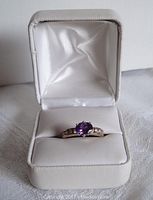 Ring displayed front-facing in white leatherette box with satin interior