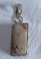 Front view of the rectangular ocean jasper stone in the sterling silver bezel pendant showing natural veining and orbs in earth tones, plus detailed bail.