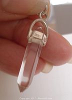 Close-up of the sterling silver cap of the pendant showing the 925 silver mark and part of the crystal point held by the fingers.