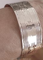 Close-up view of wavy engraved lines on the silver surface with smooth monogram area