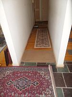 Hallway view showing runner rug with cream and burgundy intricate design, and a partial view of a smaller rug in red and navy colors.