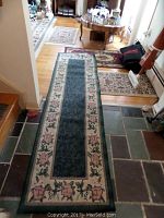 Overall view of three throw rugs and one runner rug laid on floor, showing floral border pattern and signs of use.