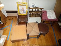 Four foot stools and a small wooden shelf in a room with wooden flooring and blue painter's tape lines visible on floor. Items show wear and fabric discoloration.