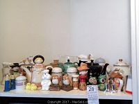 Full view of assorted ceramic teapots, figurines, salt and pepper shakers, and pitchers displayed on shelf.