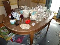 Wide view of the dining table with various glassware, dinnerware and decorative pieces arranged on top