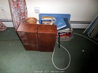 Overall view of the wooden file holders, wicker basket, clear plastic tray with office supplies, and cords on green carpeted floor.
