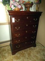 Full front view of dark wood dresser showing five drawers with brass handles and keyhole details.