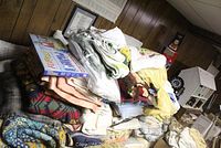 Large assortment of linens piled including blankets, throws, towels, and placemats