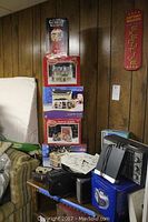 View of assortment including stacked boxes with decorative houses, boxed gumball machine, multiple radios, clock.