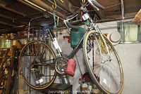 Side view of black Murray men's road bike hanging in a workshop, showing full frame, wheels, and gearing.