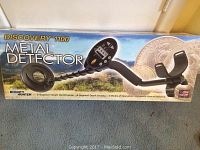 Long shot of boxed metal detector showing “Discovery 1100 Metal Detector” branding on front panel