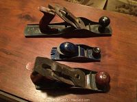 Top view of the three wood hand planes laid parallel, showing wooden handles and rounded knobs.