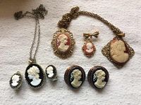 Front view of assorted cameo jewelry including 2 necklaces, several pairs of earrings, and a brooch.