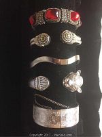 Full display of all six silver-tone bracelets and rings on black stand