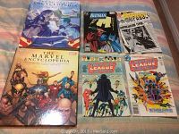 Photo showing 2 comic encyclopedias and 4 comic books arranged on fabric.