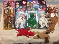 Photo showing eight Ty Beanie Babies including four in original packaging (Britannia, two Glory bears, Erin) and four loose bears of various colors and styles.