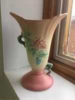 Full view of an 8 inch tall Hull U.S.A. pottery vase with floral decorations; pale cream, green, pink, and blue colors; flared top and round base with handles.