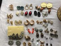 Full overview of 32 pairs of clip and screw on costume earrings in various designs and colors on white cloth background