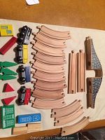 Complete set of wooden train track pieces, wooden train engine and cars, and accessory pieces laid out on a flat surface.