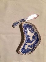 Top view of kidney-shaped Blue Willow pattern butter dish with gold trim and matching butter knife with ceramic handle featuring Blue Willow design and metal blade.
