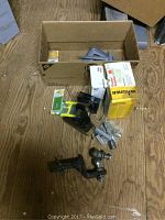 Workshop lot items laid out on floor including trailer hitch, clamp, boxes, and hardware