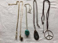 Full lot of 5 necklaces laid out on a white fabric background showing chains and pendants.