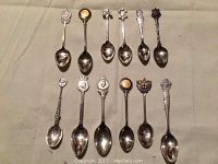 Full view of the 10 collectible spoons laid out showing different royal motifs and minor tarnish.