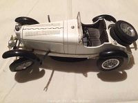 Top view of a white 9 inch vintage Mercedes model car with detailed interior and spare tire at back.