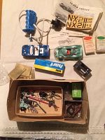Top-down view of slot cars, controller, decals, instructions, parts, and packaging on white surface.